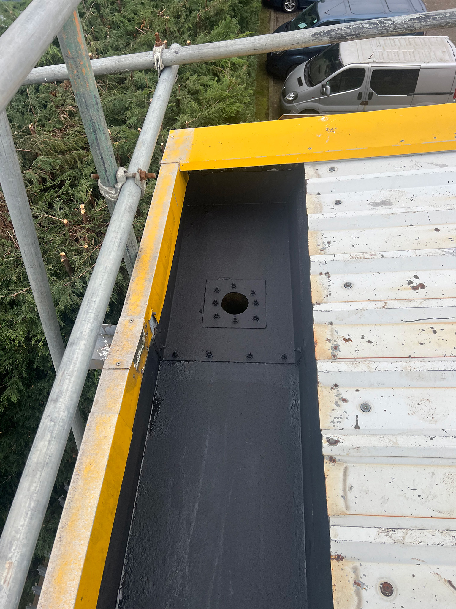 Close-up of a steel gutter downspout outlet socket treated and primed with Everbuild Black Jack 902 primer during the gutter refurbishment phase of the Gateshead PVF2 roof project