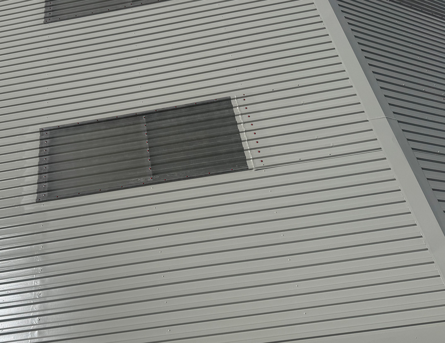 Section of a commercial roof after full coating with a rooflight panel visible