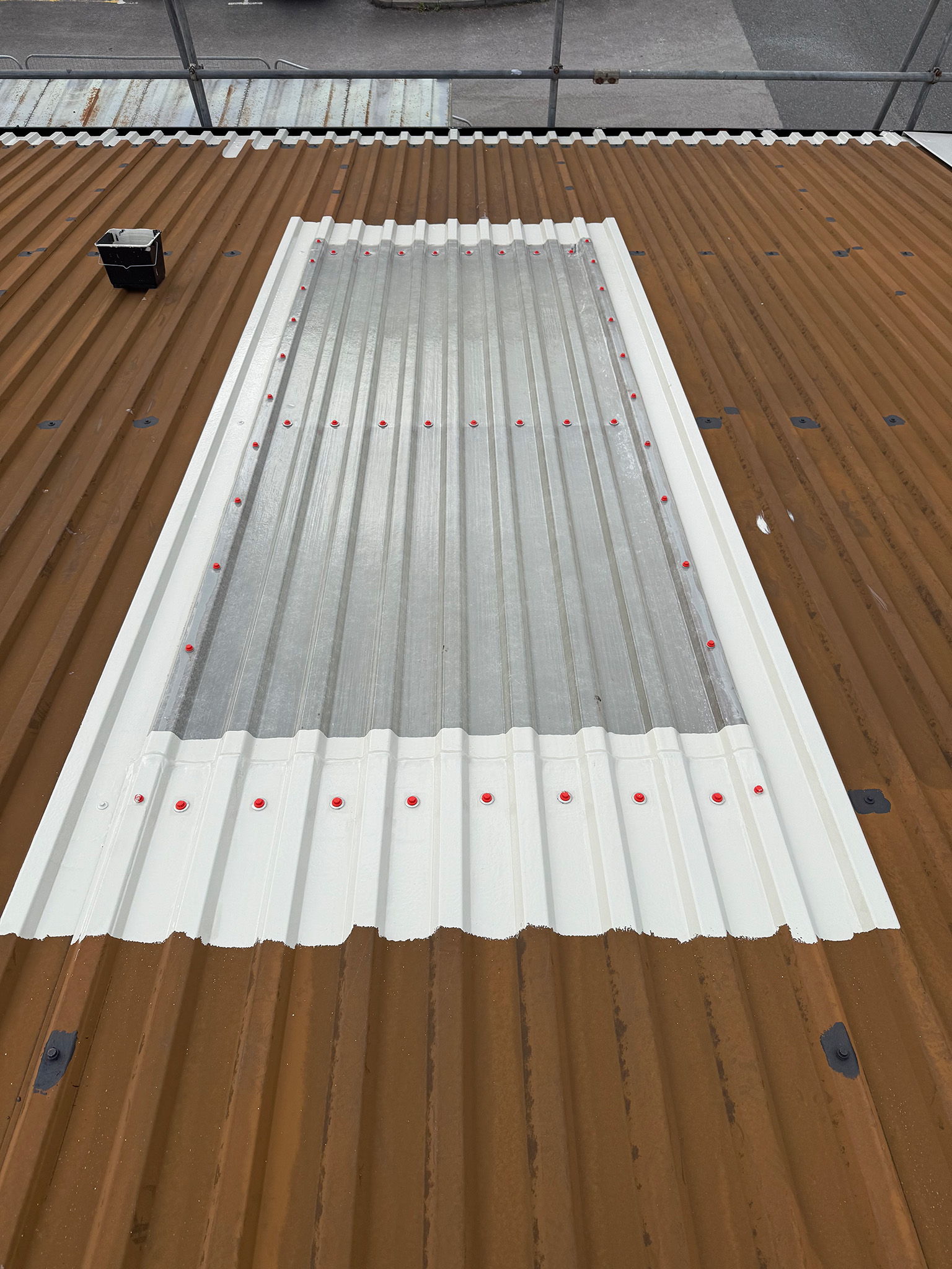 Rooflight overlap with sheet ends and roof fixings primed on a commercial roof