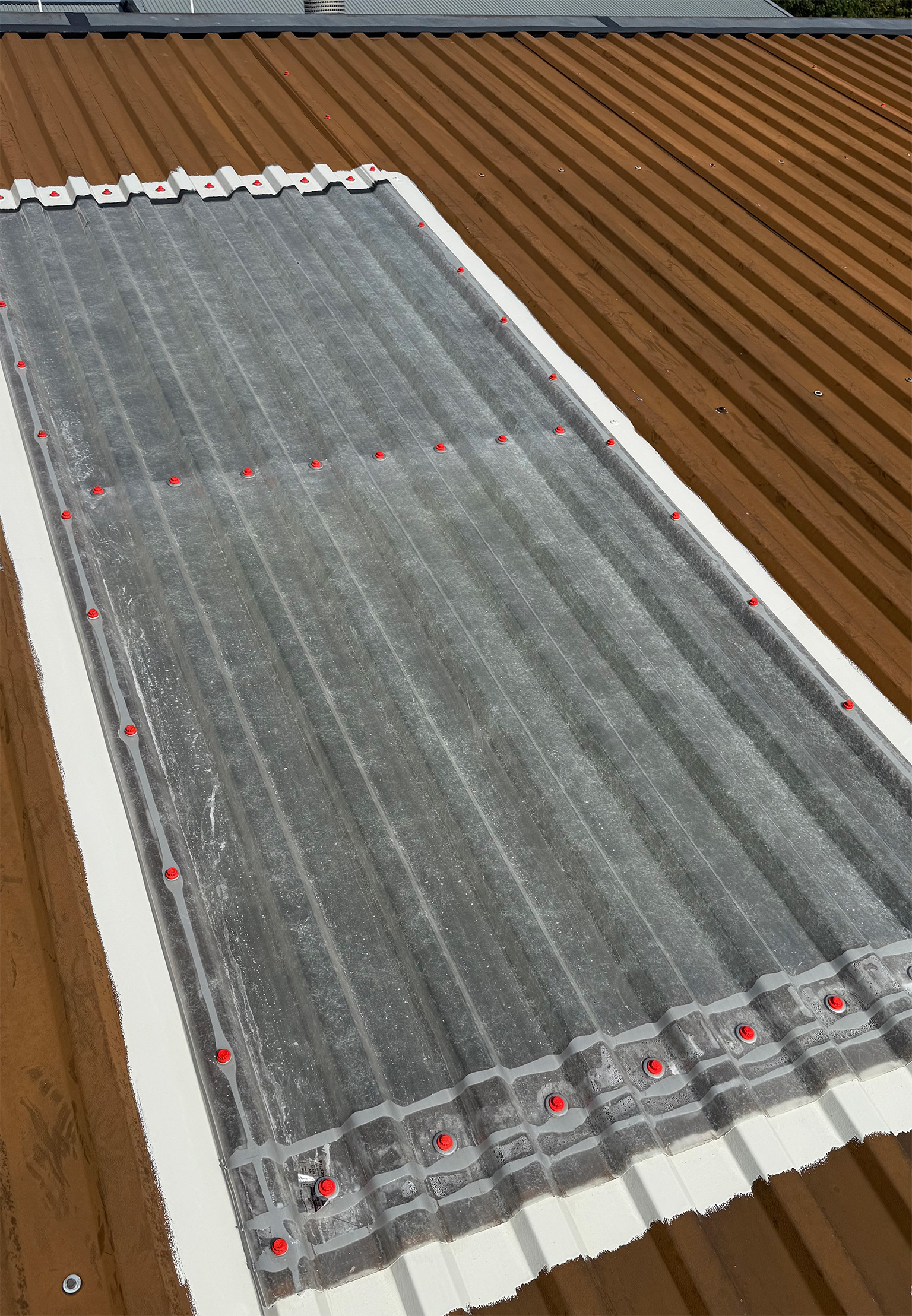 Rooflight edges treated with mastic and primer on a commercial steel roof
