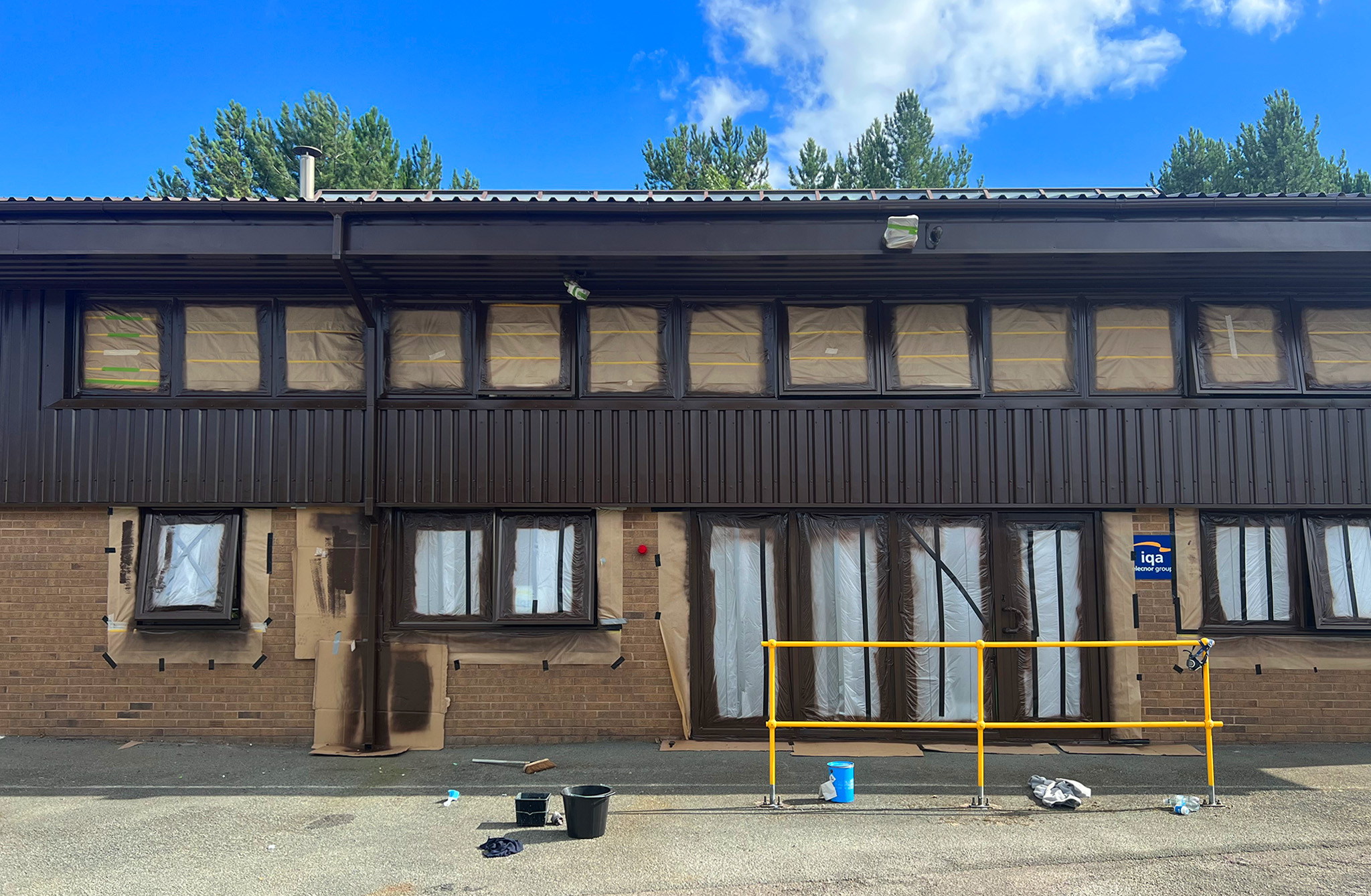Commercial cladding refurbishment ongoing at Bodelwyddan with masked windows and safety barrier in place