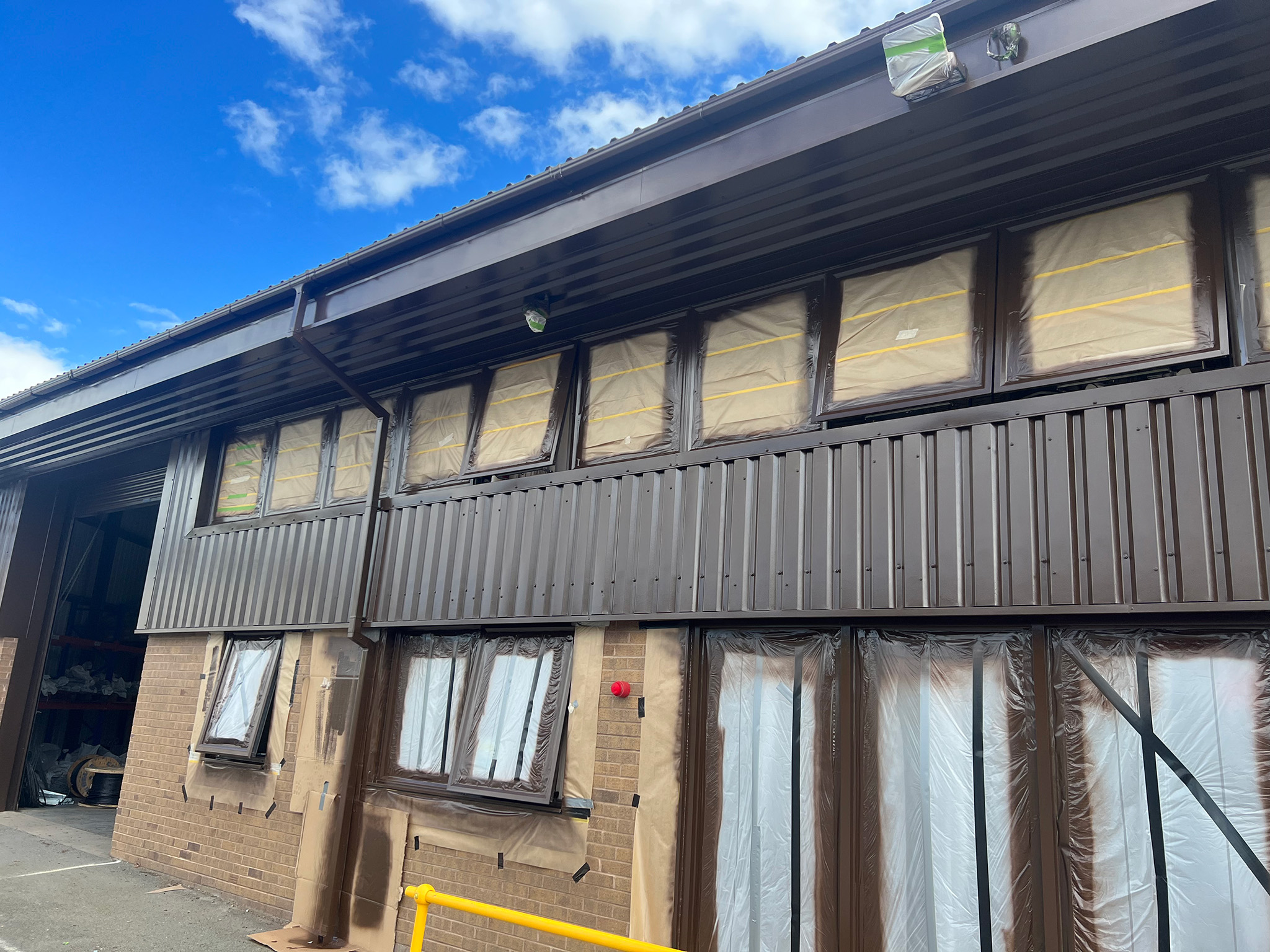 Spray applied Tikkurila Temadur 20 chestnut and mahogany brown to office cladding window frames soffits gutters and doors